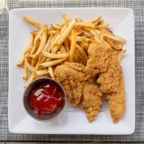 Crispy chicken tenders and golden french fries with a side of ketchup on a white plate.