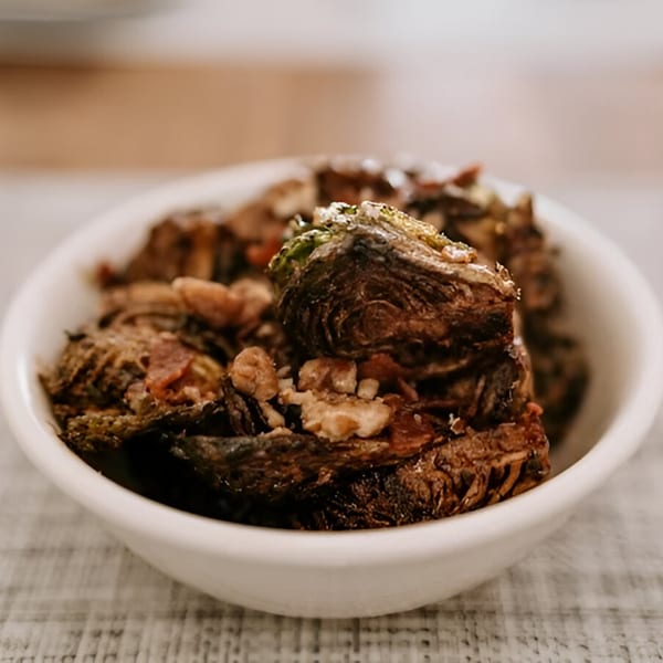 Close-up of a white bowl filled with crispy fried oysters, garnished with herbs.