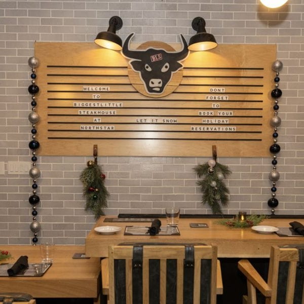 Biggest Little Steakhouse sign with a bull logo, holiday decorations, and set tables.