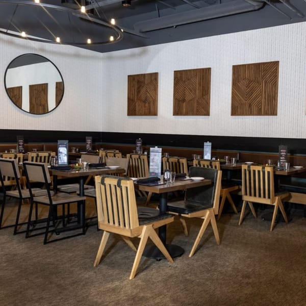 Interior of Biggest Little Steakhouse with set tables, wooden chairs, and modern wall art.