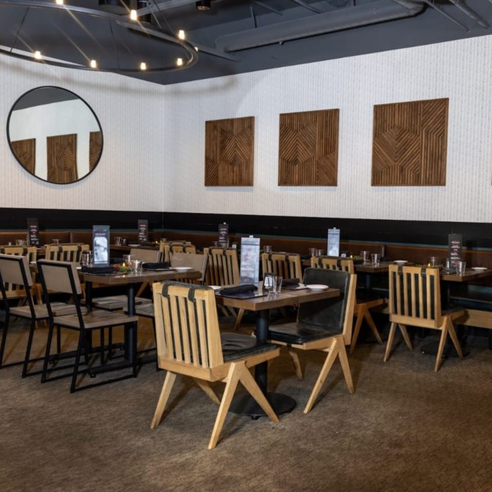 Interior of Biggest Little Steakhouse with set tables, wooden chairs, and modern wall art.